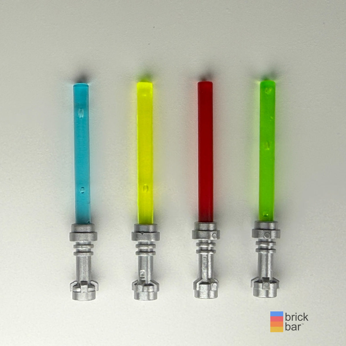 Four complete LEGO lightsabers with silver hilts; left to right: Trans-Light Blue, Trans-Neon Green, Trans-Red, Trans-Bright Green. Sold individually.